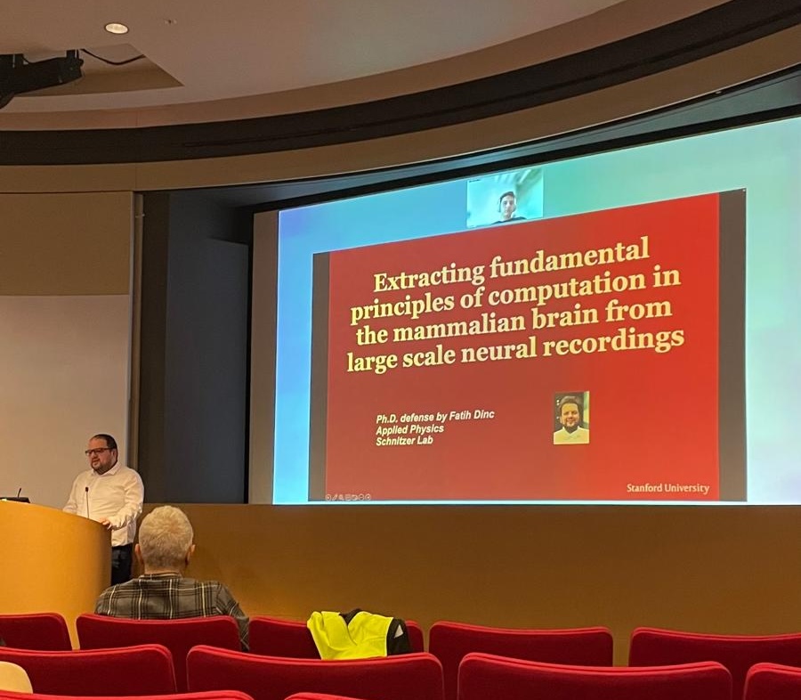 Speaker presenting a slide titled “Extracting fundamental principles of computation in the mammalian brain from large scale neural recordings” in a lecture hall.